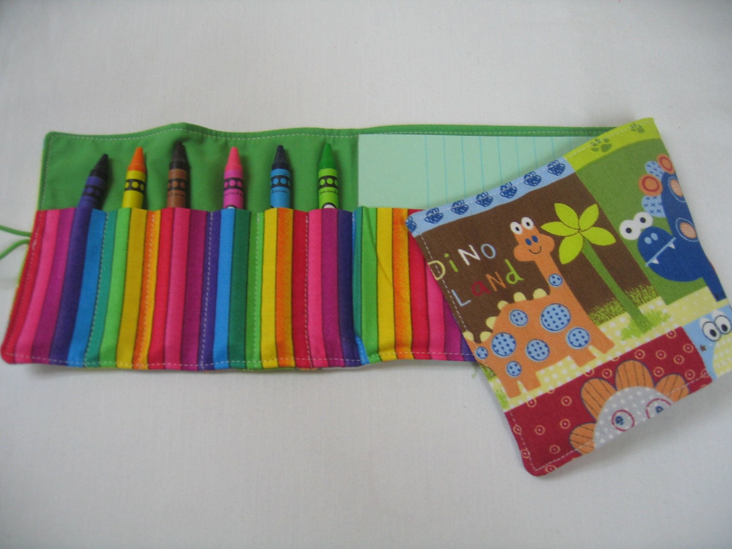 Baby Dino Mater Crayon Tote in a colorful print complete with 12 crayons and a paper pad