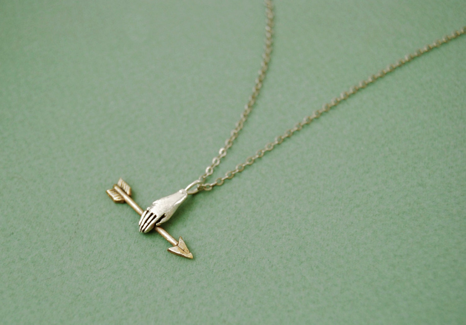 Hand with golden arrow necklace