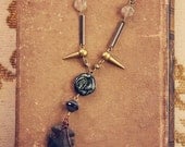 zara.  a black and gold spiked arrowhead necklace.