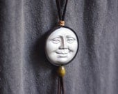 moonshine.  a brown deerskin wrapped moon face necklace.