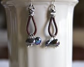 Earrings made with sterling silver crimp ends, distressed brown leather and wire wrapped peacock colored freshwater pearls