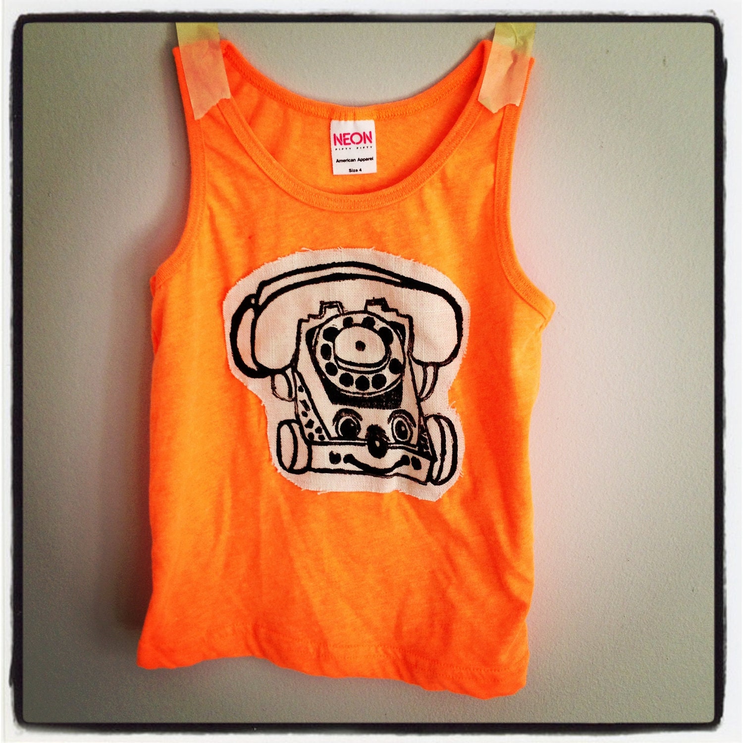 Neon orange tank with retro toy phone printed on neutral linen:)