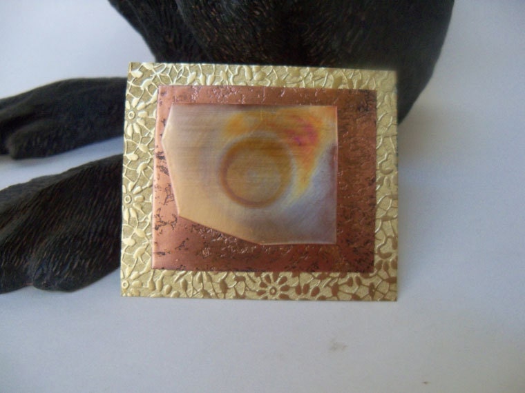 Copper brooch made from copper and brass sheet metal that was heat treated.