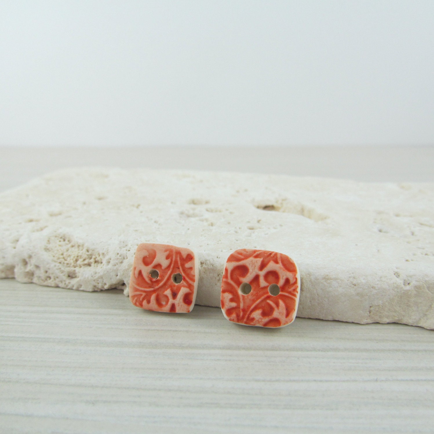 Handmade polymer clay organic square buttons in brick red faux ceramic floral texture.