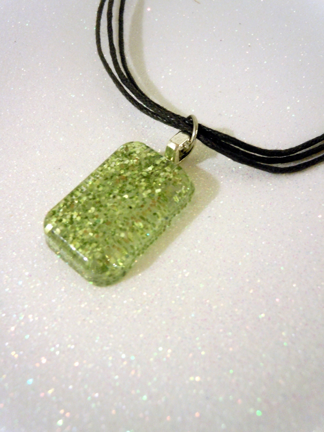 Green glitter charm on black cord necklace