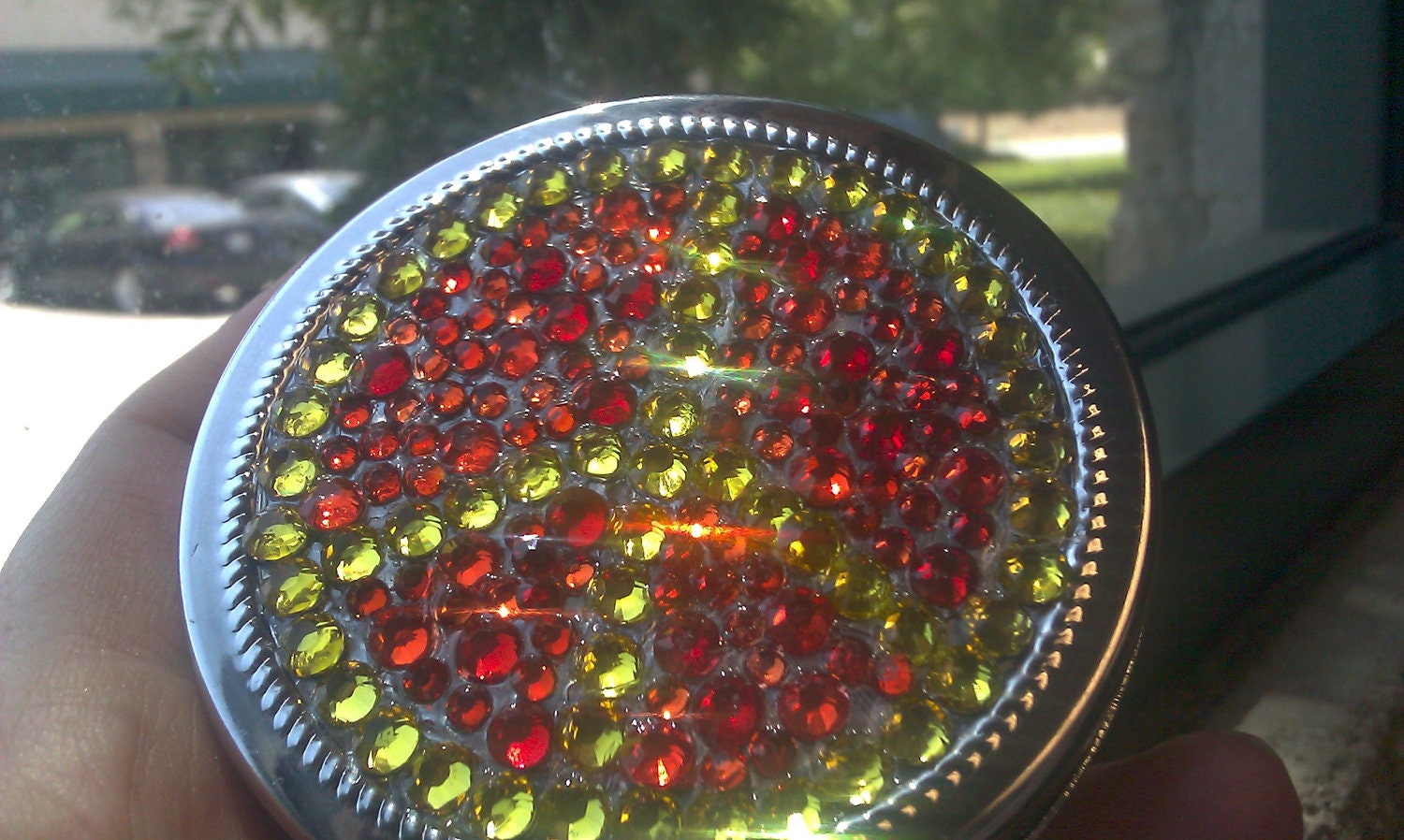 Large Round Silver tone Compact with an Encrusted Peace Sign in Yellow Rhinestones Surrounded by Red, Orange and Clear Rhinestones.