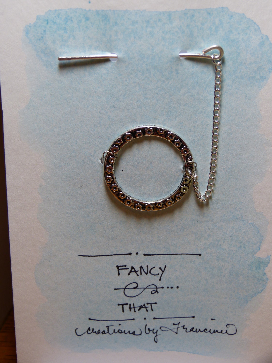 A delicate silver shawl pin or sweater closure