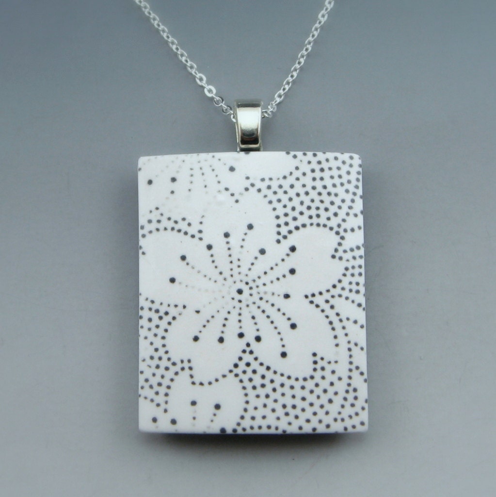 Modern polymer clay pendant on chain with a black and white flower design and a pop of color