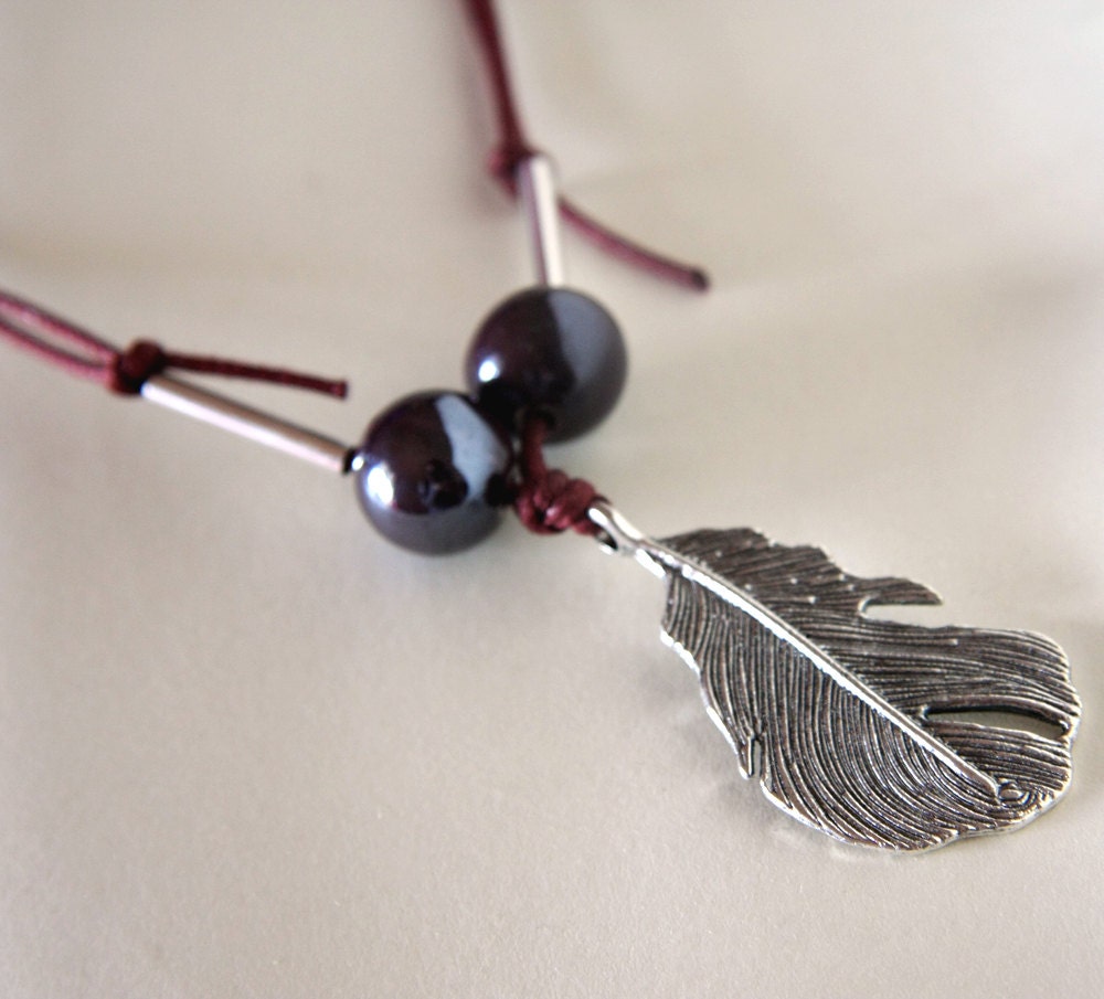 feather tribal pendant with metal and ceramic beads on waxen cord