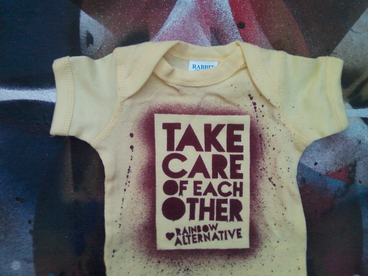 LGBT Pride baby onesie hand stenciled and spray painted by Rainbow Alternative on Etsy
