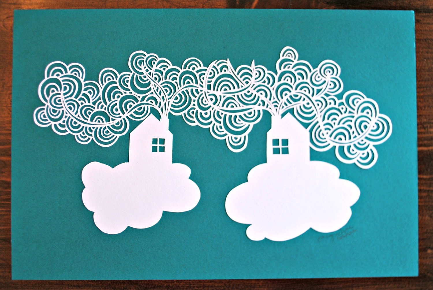 Cut paper illustration of houses and clouds, floating amongst the clouds