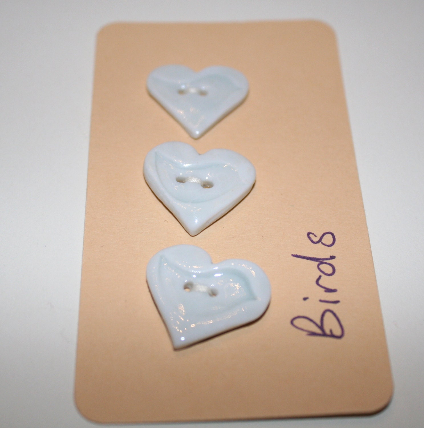 Porcelain ceramic, white heart buttons with a bird impressed design