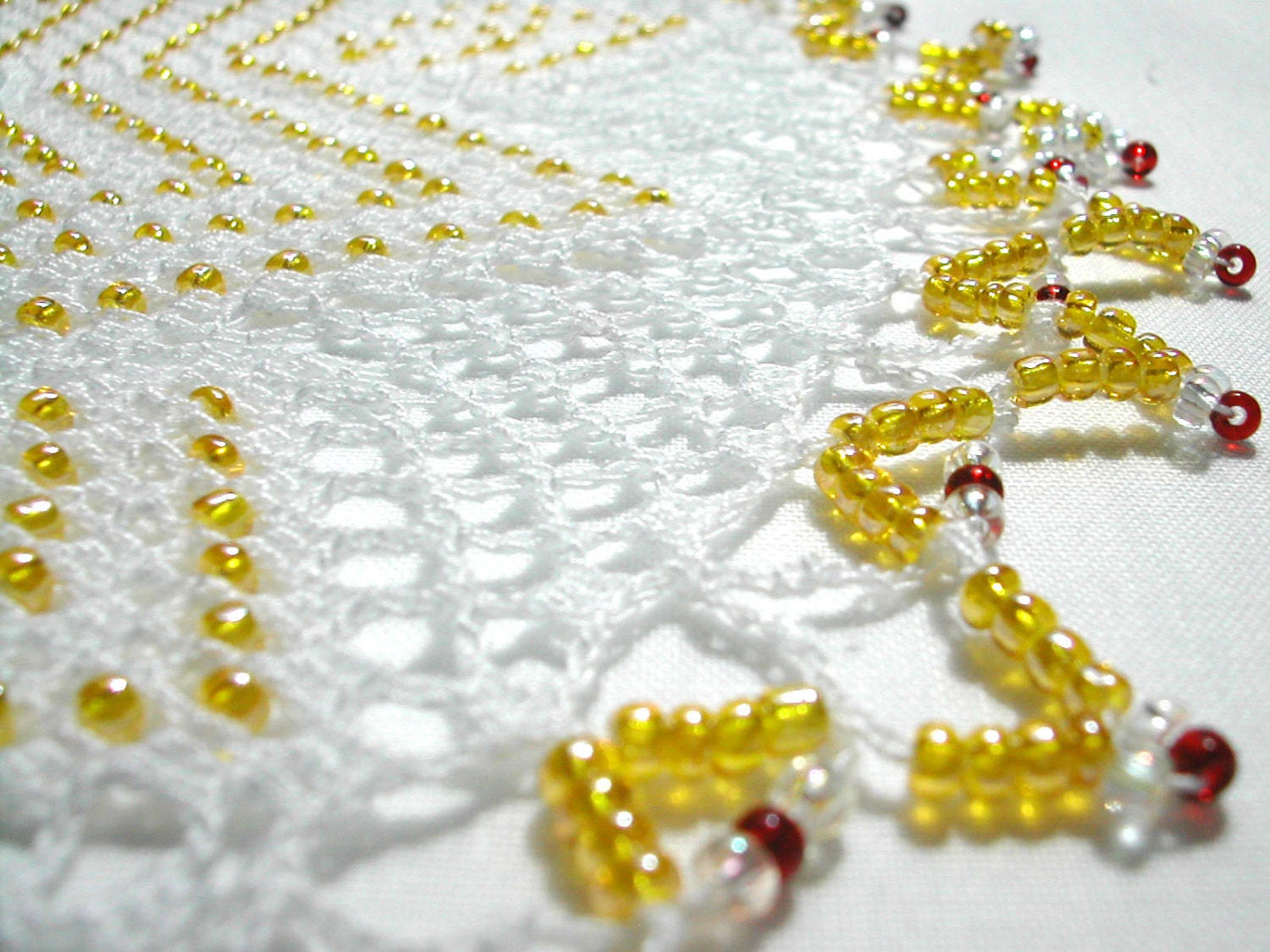 white crochet doily with yellow glass beads