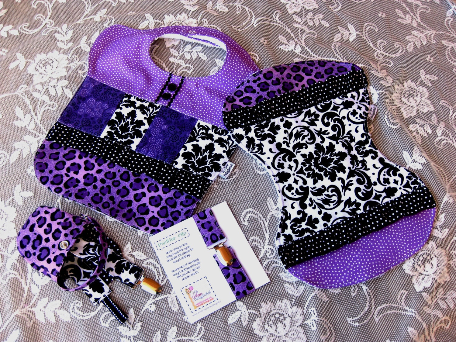 Baby gift set with bib, burp cloth, pacifier pocket, and two pacifier clips in purple, black and white animal prints