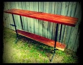 Industrial bar height walnut table supported by black threaded pipe