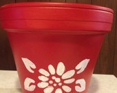 Beautiful bright red painted clay pot with a white floral design .