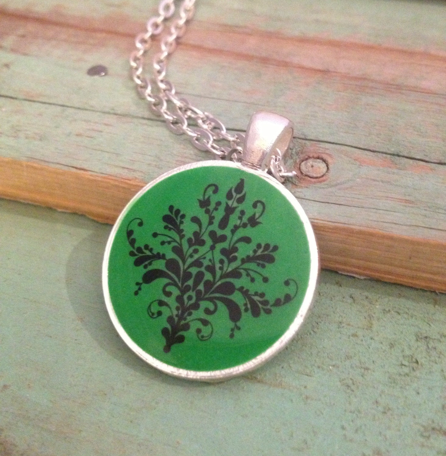 Green pendant necklace with black motif. Silver  finish. 1 inch