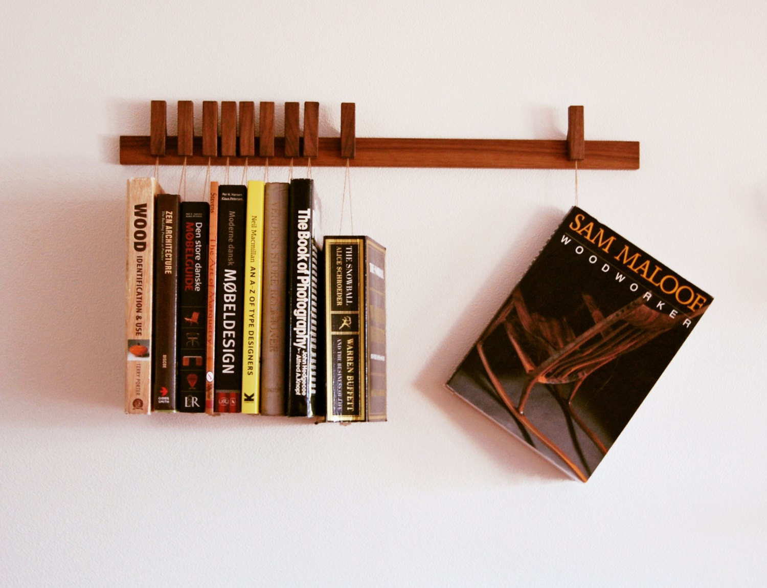 Custom made wooden book rack in Walnut. Pins also work as bookmarks.