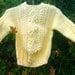 Child's handknit yellow aran sweater with shoulder opening.