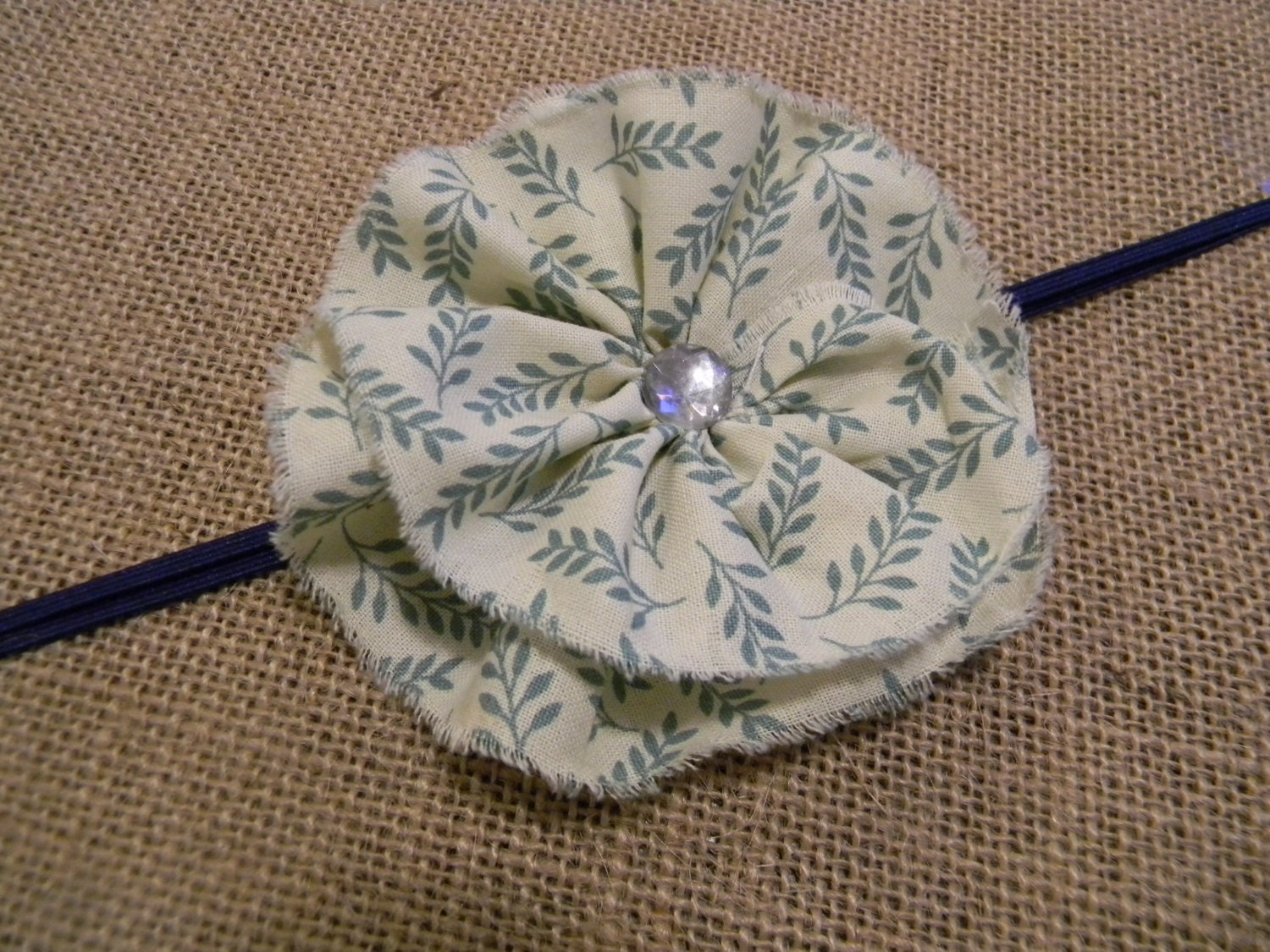 Baby ruffled flower headband - cream fabric with green leaf ruffled flower on navy skinny elastic