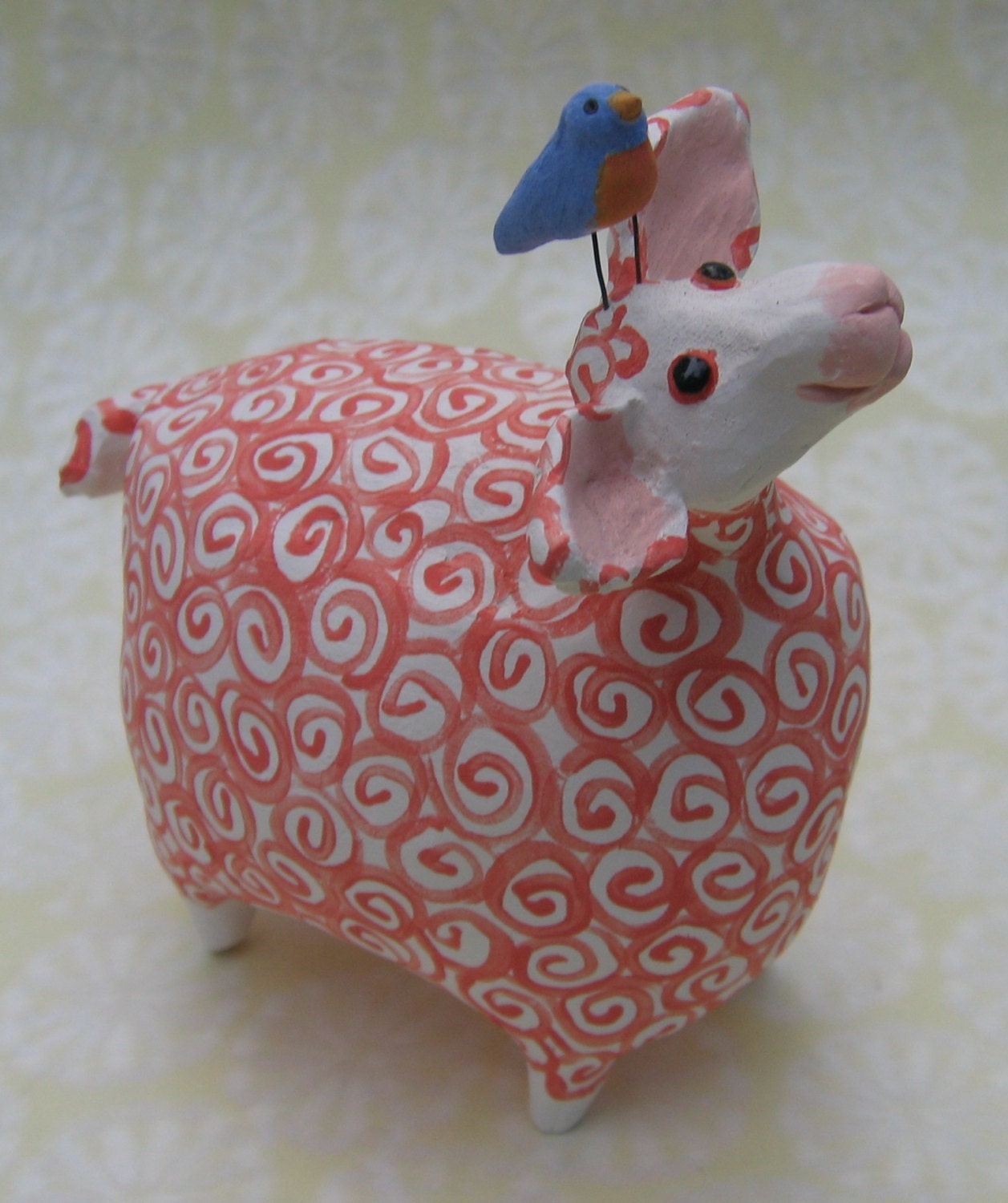 Red and white ceramic sheep with bluebird perched on head