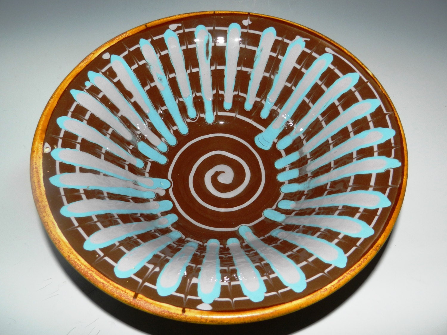 Ceramic serving bowl with colored slip decoration and golden brown glaze