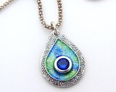 Silver and Enamel Sparkling Peacock Swirl Teardrop Pendant. Handmade gem set with a lab Sapphire on sterling silver chain.