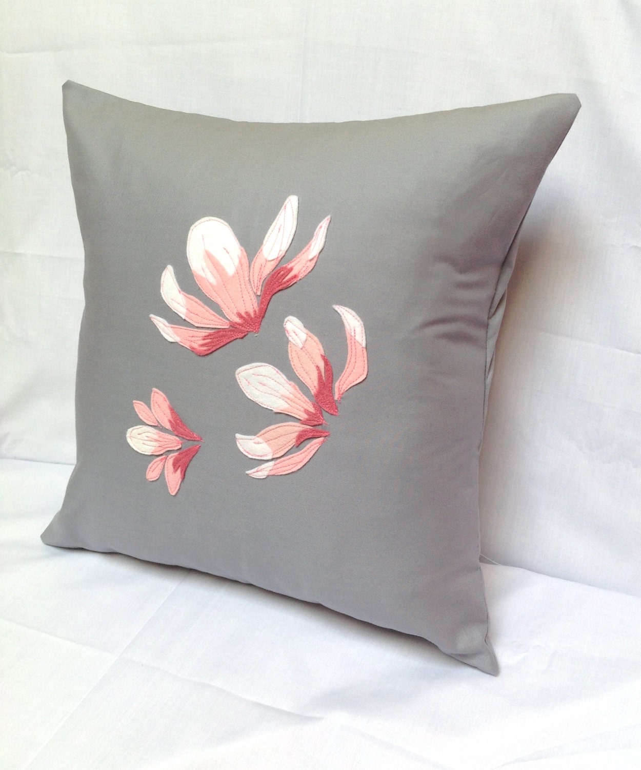 Pink felt Magnolia flowers on a grey cotton pillow