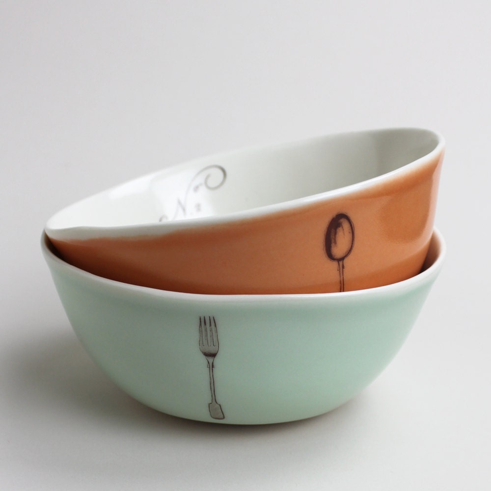 set of two rustic bowls, one orange with spoon, one turquoise with fork