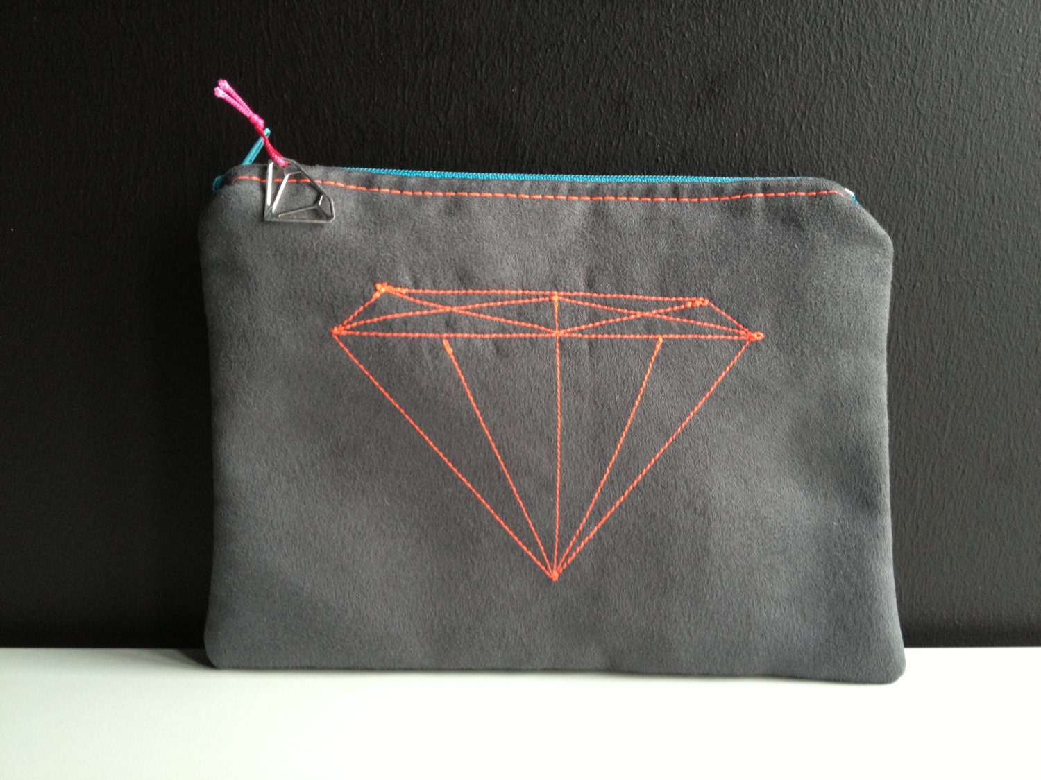 dark grey pouch made of faux leather with stitched diamond in neon pink