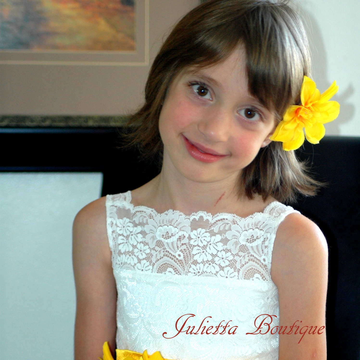 Ivory  flower girls dress with a tulle skirt flower sash and petals in the skirt.  A white dress for a wedding with a lace bodice