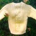 Child's handknit yellow aran sweater with shoulder opening.