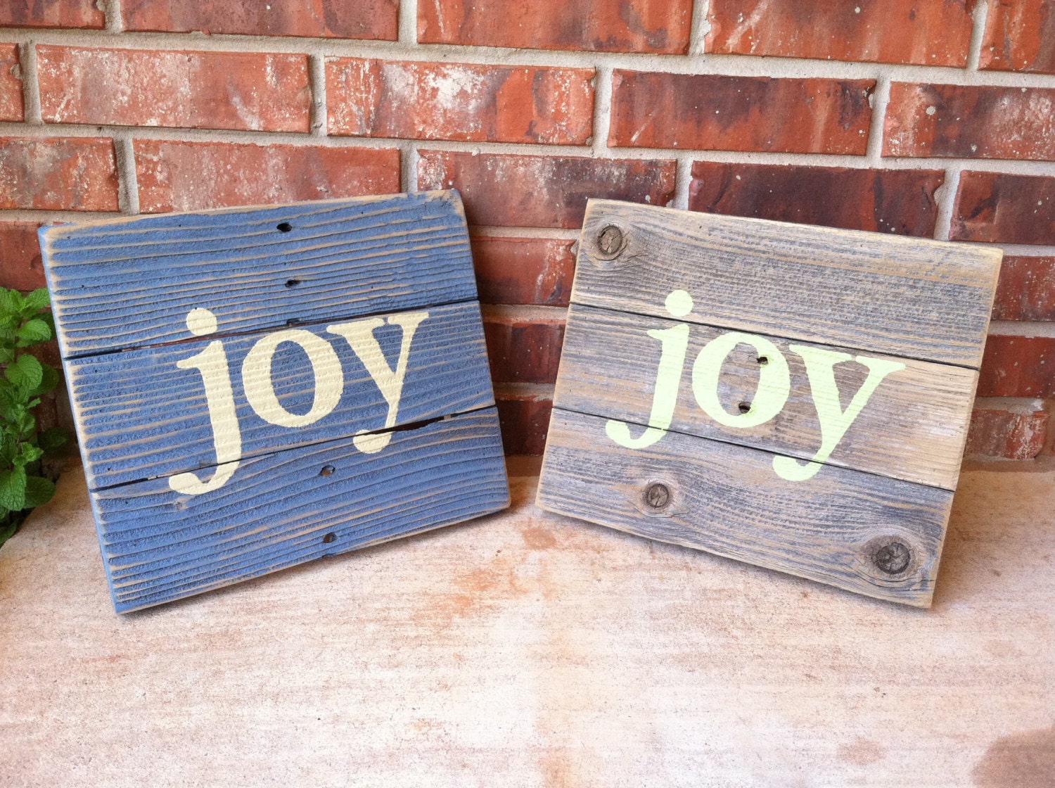 Two JOY signs one in slate blue and another in natural weathered cedar