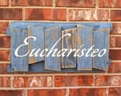 EUCHARISTEO sign in white paint on slate blue dry brushed and sanded fence wood
