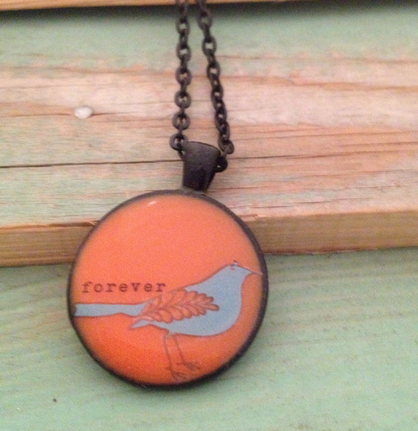 Orange pendant necklace with blue bird and 'forever' quote. Black finish. 1 inch