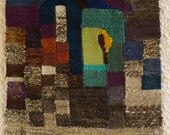 fiber art wall hanging with a face shaped ceramic bead