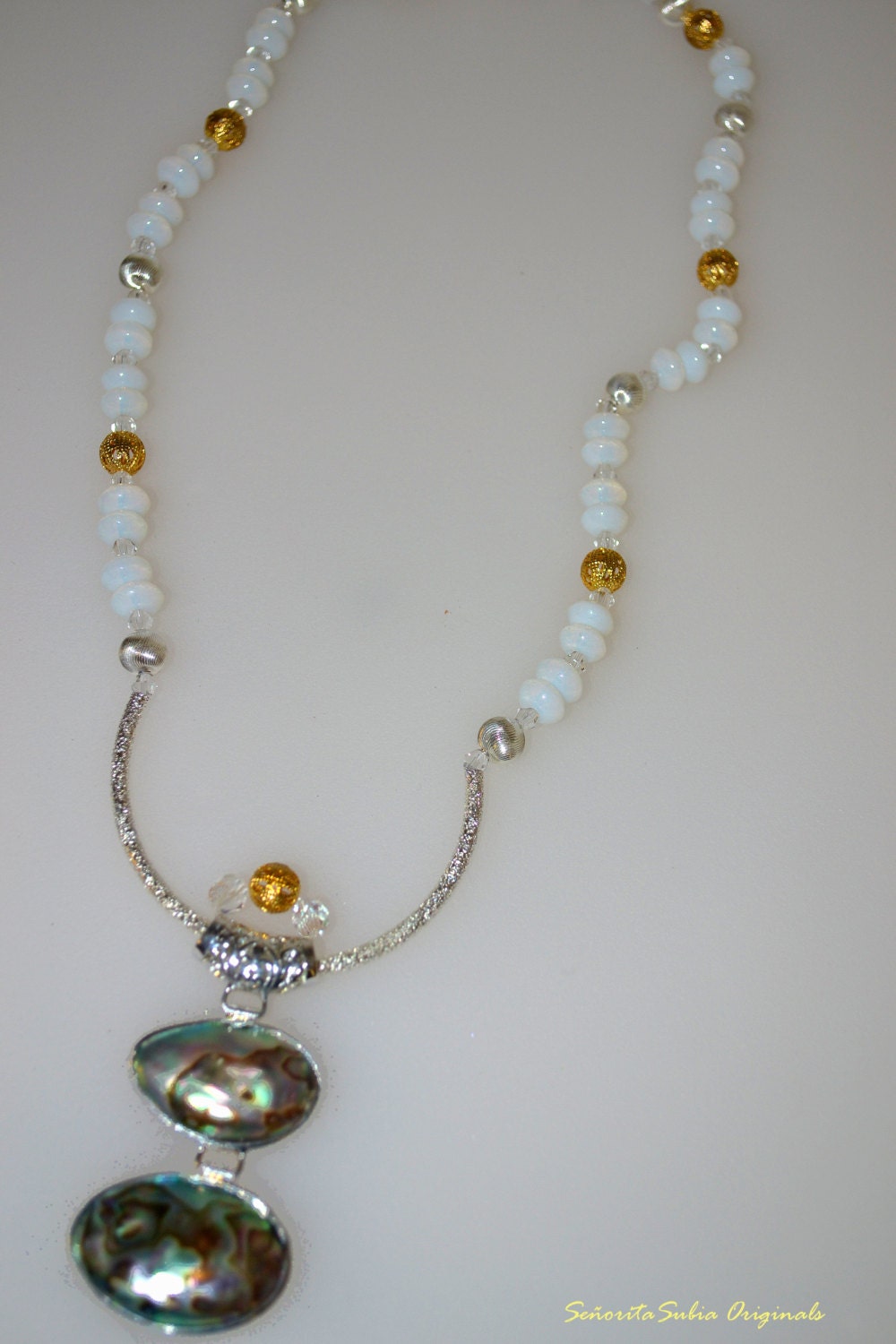 Mother of pearl pendant with translucent crystals,  gold tone, silver tone accents and white glass beads.
