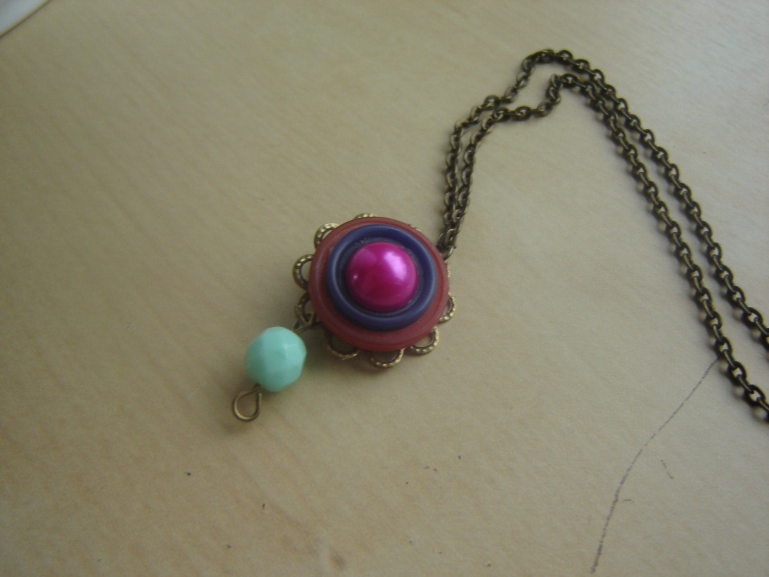 Long antique brass statement necklace with orange & purple vintage buttons, faux pearl cab, and mint Czech glass bead