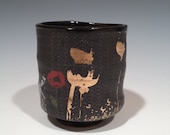 Black cup with platinum patterns and poppies.