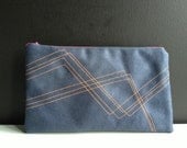 dark blue pouch made of faux leather with stitched geometric lines in neon red