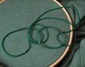 Two metallic green necklaces with accents of pearl