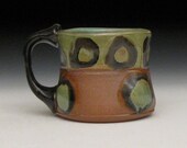green top raw bottom with green and black circles and black handle mug