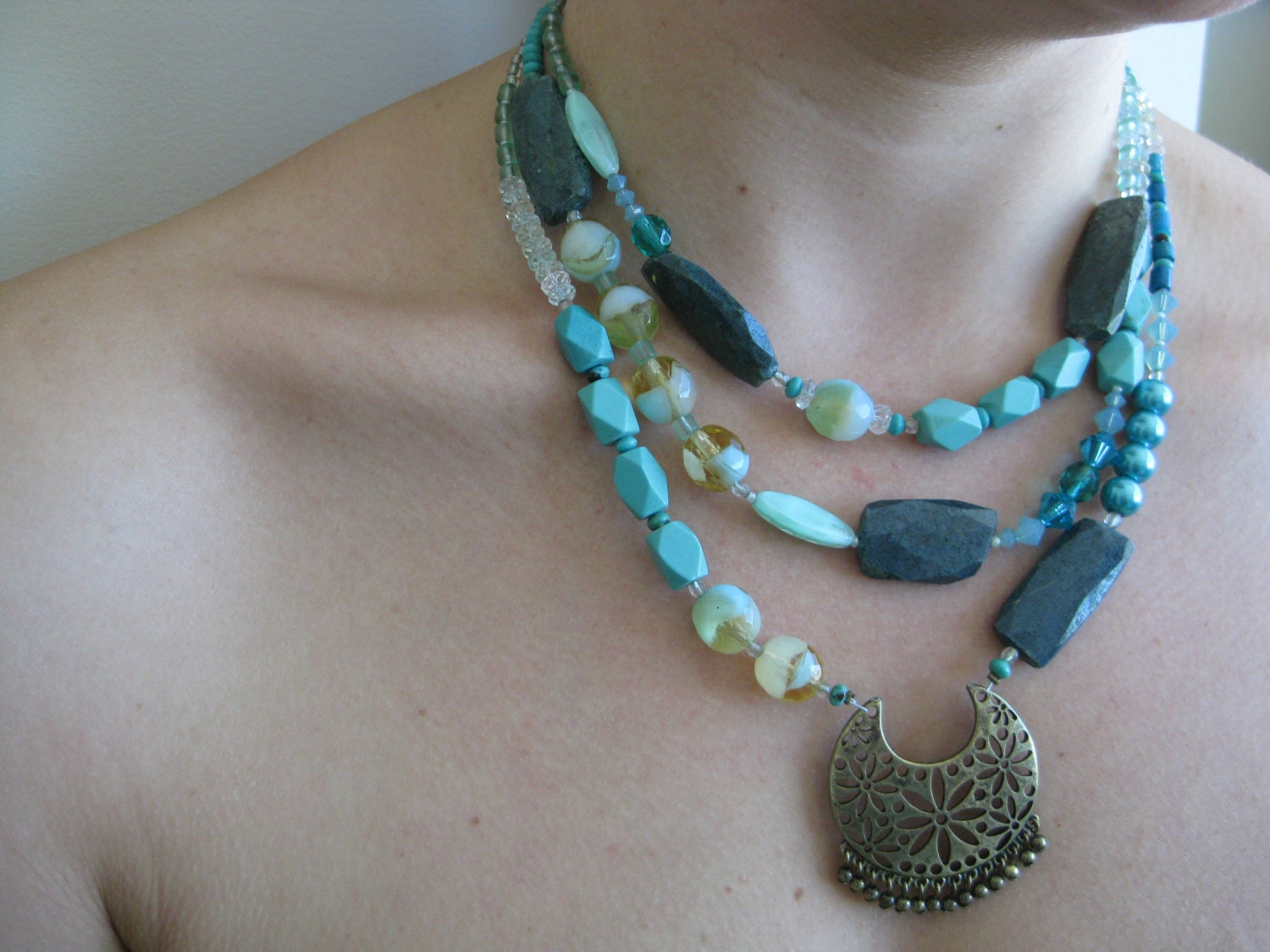 Triple-strand necklace of turqoise and blue beads with bronze feature pendant