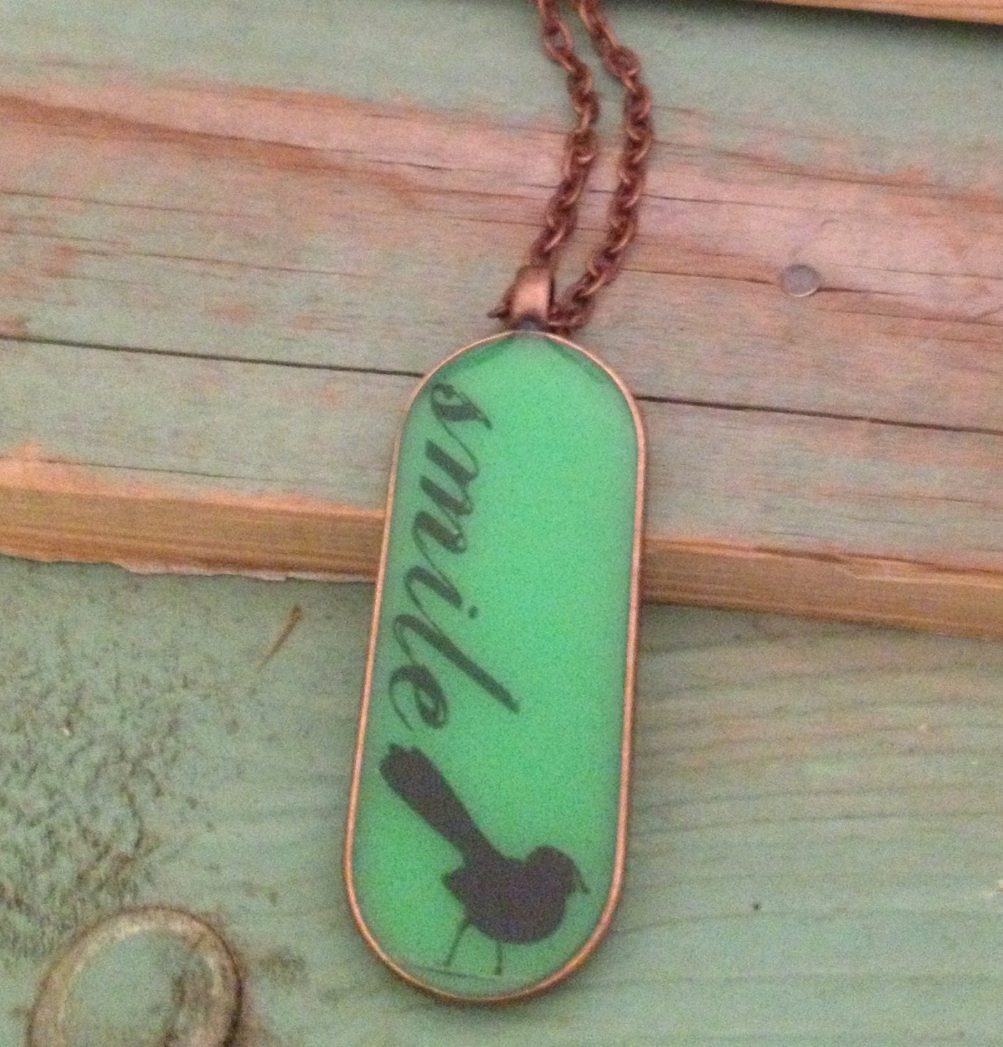 Green resin pendant with bird and 'smile'. Large oval 45mm x 18. Copper finish