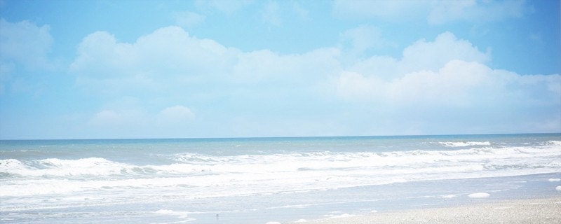 where the ocean meets the sky... ocean panoramic photo with calm blue sky, white sand beach, and waves for sea lovers