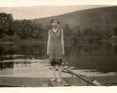 1920's photo.Woman standing in rowboat in middle of lake