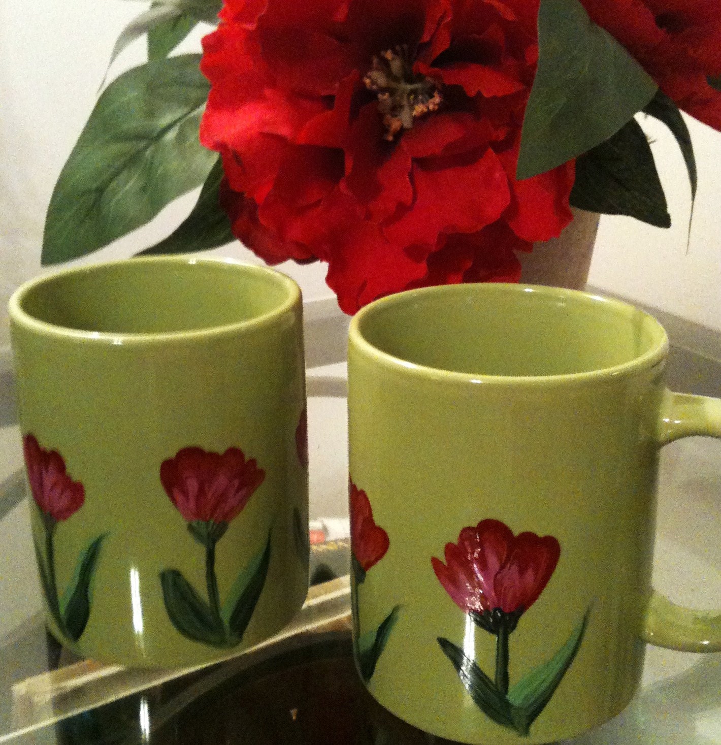 A pair of bright green mugs with red flowers