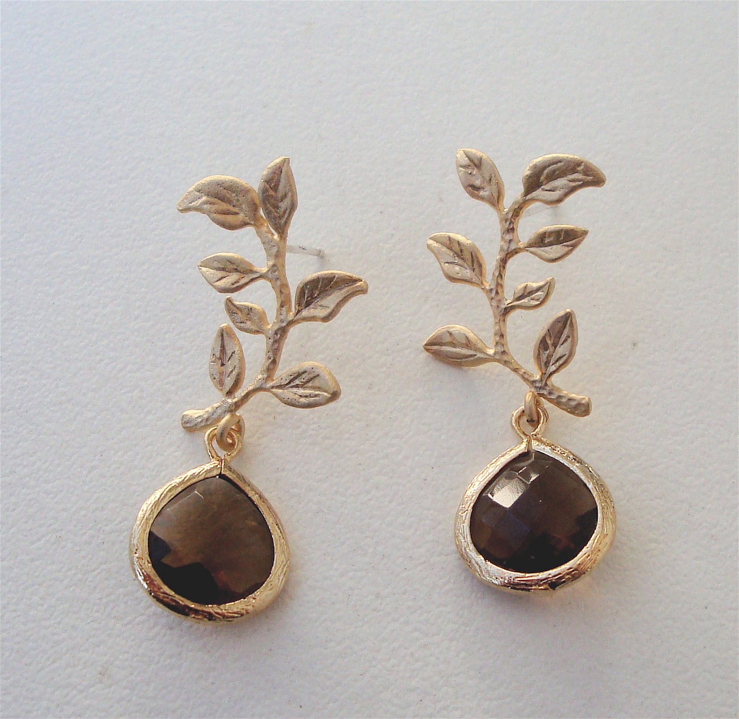 Matte gold plated over brass drop earring with a smoked topaz crystal pendant, branch with leaves and a  sterling silver post.
