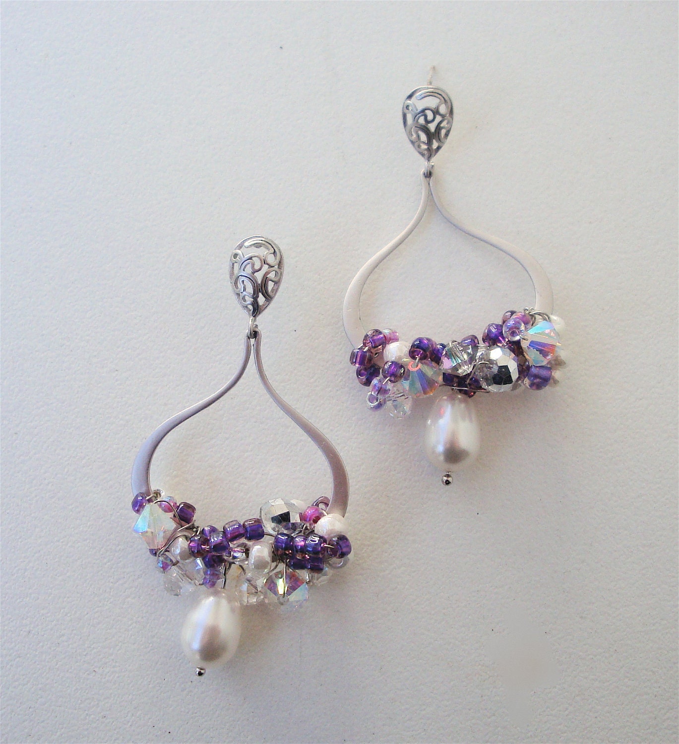Matte silver hoop earring with paisley ear pad and sterling silver post with swarovski crystals and seed beads all wire wrapped together wit