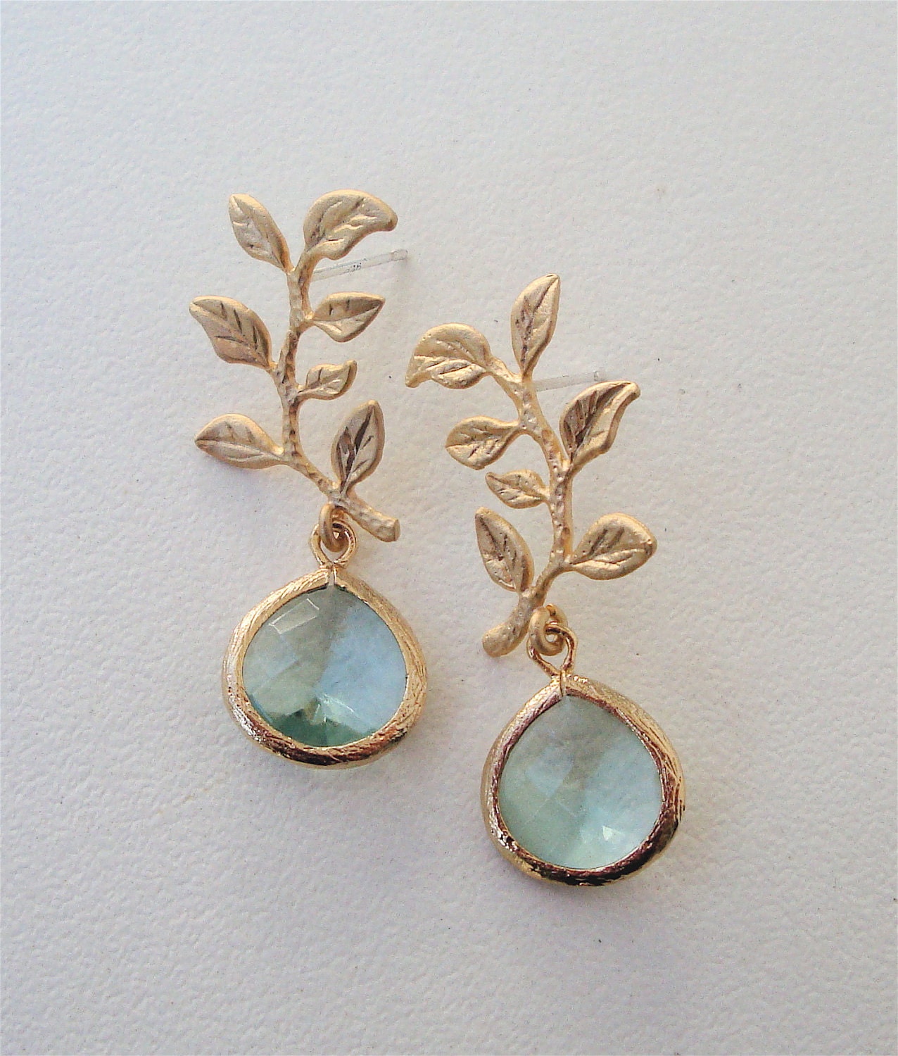 Matte gold plated over brass drop earring with a Erinite crystal pendant, branch with leaves and a sterling silver post.
